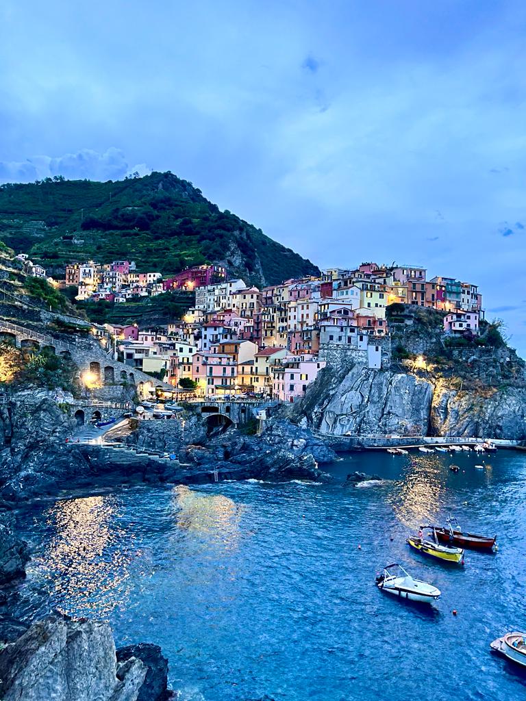 Stunning evening view of Manarola, one of the enchanting villages in Cinque Terre, Italy, with colorful buildings lit by warm sunset light.