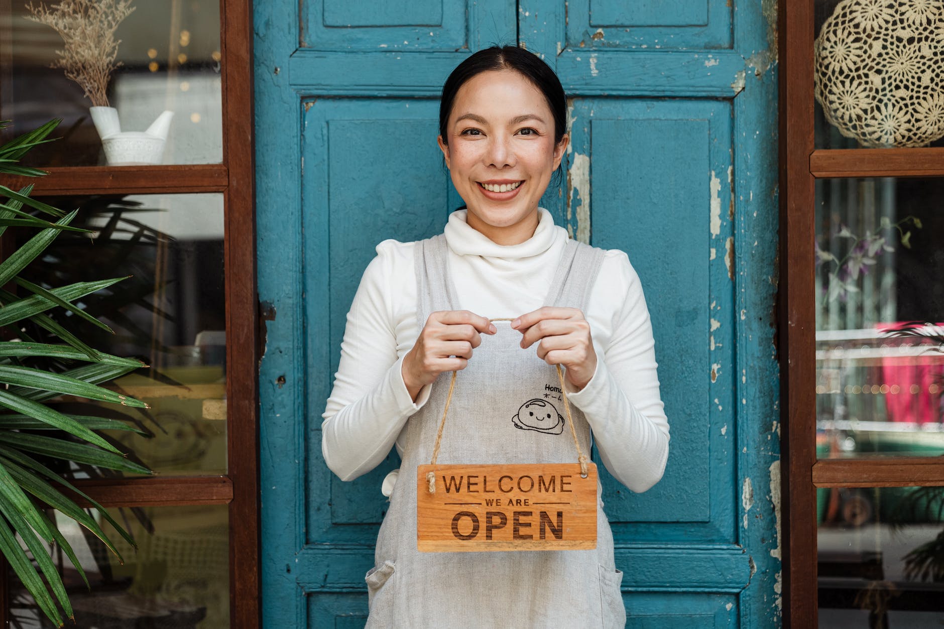 ethnic female cafe owner showing welcome we are open inscription