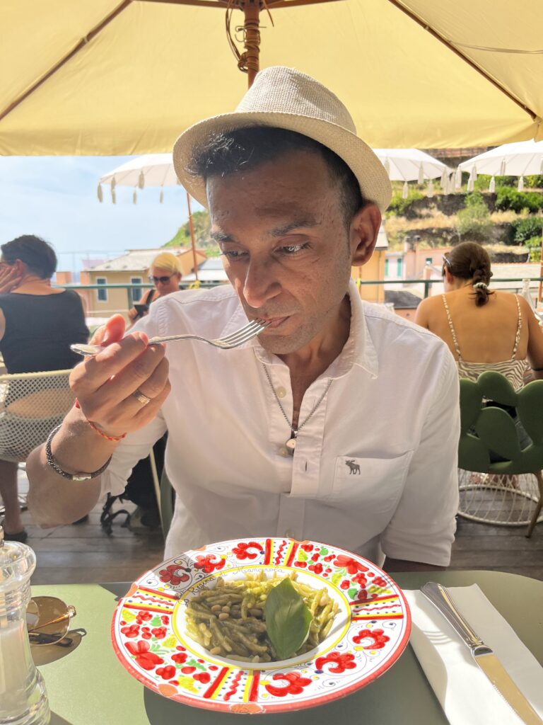 Deeshen savoring a delightful plate of vegetarian pasta in the scenic setting of Cinque Terre, Italy.