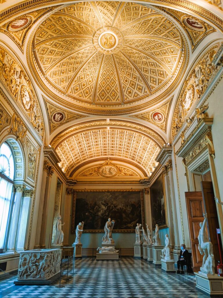 Grandeous room in Uffizi Gallery with people meeting Uffizi Gallery dress code, and sculptures and paintings.  Uffizi Museum is the best art museum in Florence Italy.